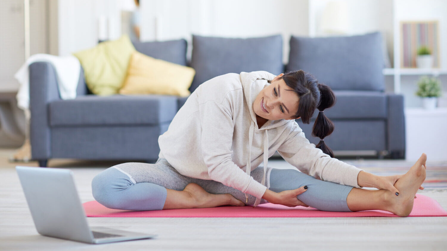 Woman stretching and doing an online yoga class.